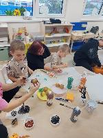 Děti společně s rodiči tiskají bramborová razítka na látkové tašky.