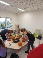 Rodiče vydlabávají a vyřezávají dýně.