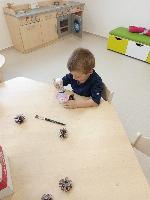 chlapeček maže lepidlem šišku